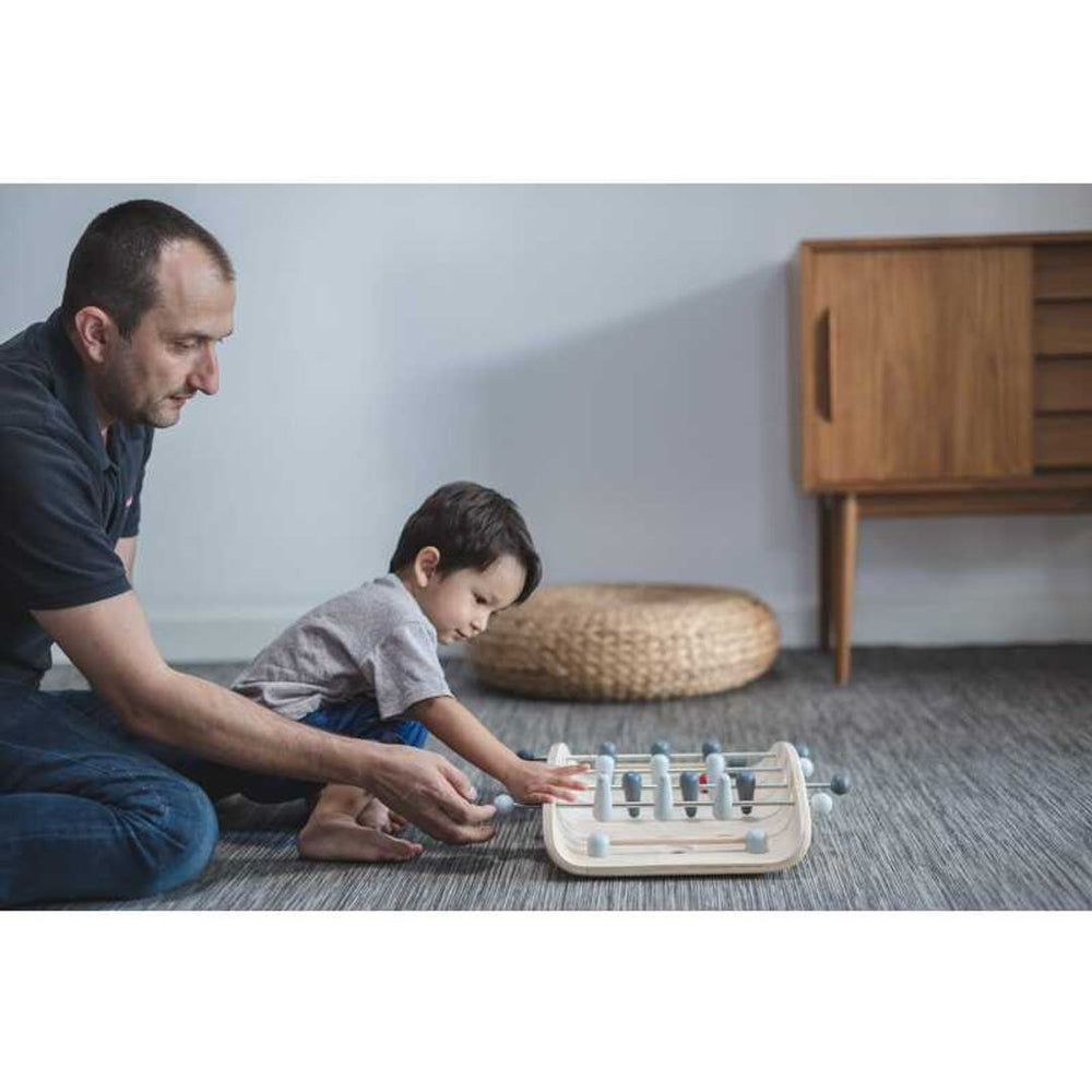 Father and son playing with PlanToys - Wooden Tabletop Soccer Game on floor