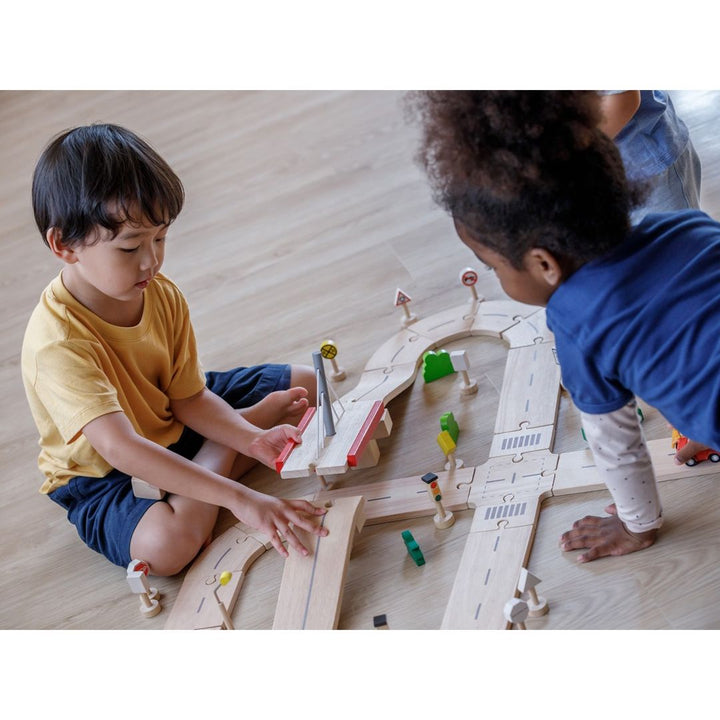 Boy opening drawbridge of PlanToys - Wooden Road System Play Set