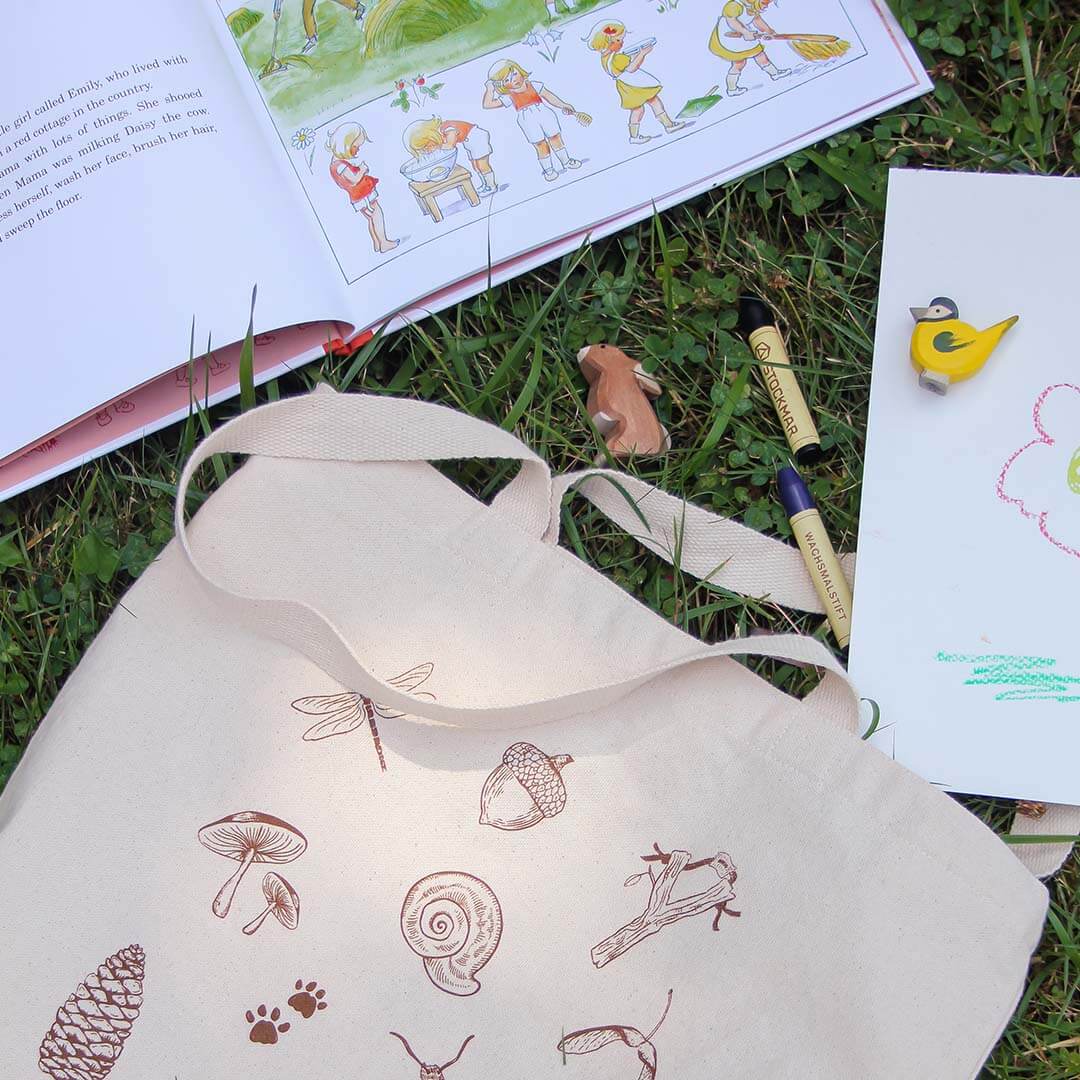 Nature Treasure Hunt Canvas Book Tote in grass with book and toys.