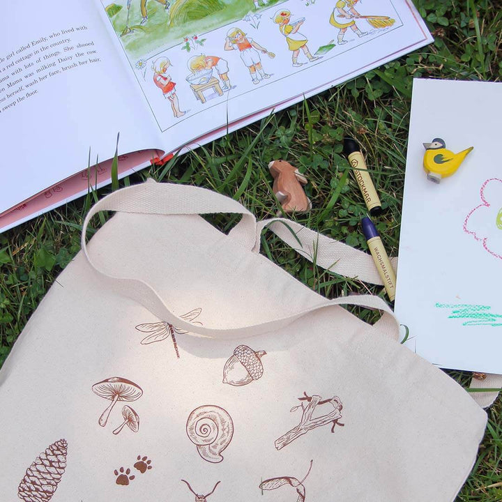 Nature Treasure Hunt Canvas Book Tote in grass with book and toys.