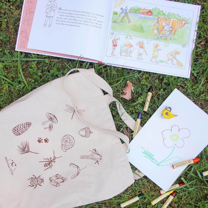 Nature Treasure Hunt Canvas Book Tote outdoors with book and toys.