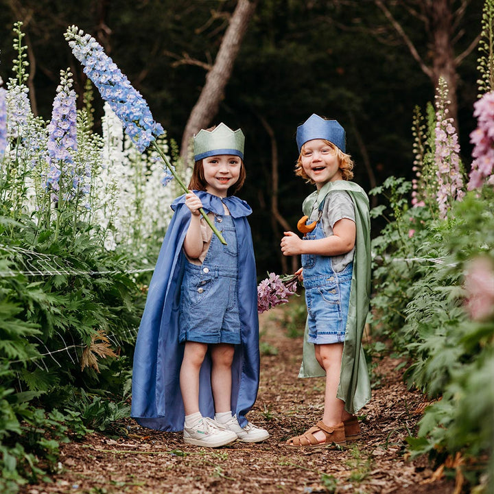 Sarah's Silks Northern Coast Magical Silk Dress Up set with reversible crowns, cape and streamer being used by two kids in a purple flower field.