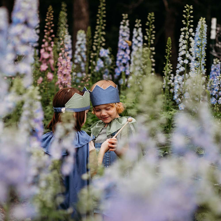 Child wearing Sarah's Silks Northern Coast Playsilk crown and cape in a flower field.