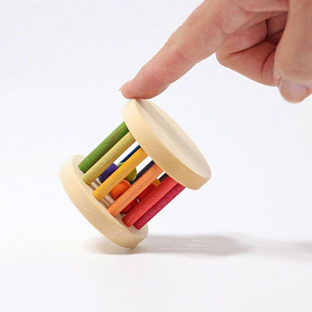 An adult sized hand holding the Grimm's Spiel & Holz - Grimm's Mini Rolling Wheel - Bella Luna Toys