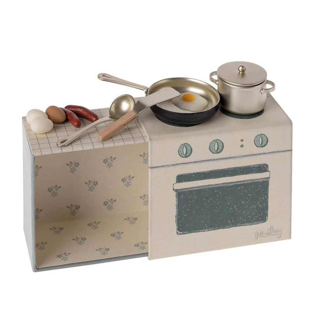 Maileg Dollhouse Stove and Cooking Set with pan, pot with lid, 2 white eggs, one brown egg, 2 sausages, 1 fried egg, spatula, and soup spoon, plus stovetop with 2 burners and 3 knobs