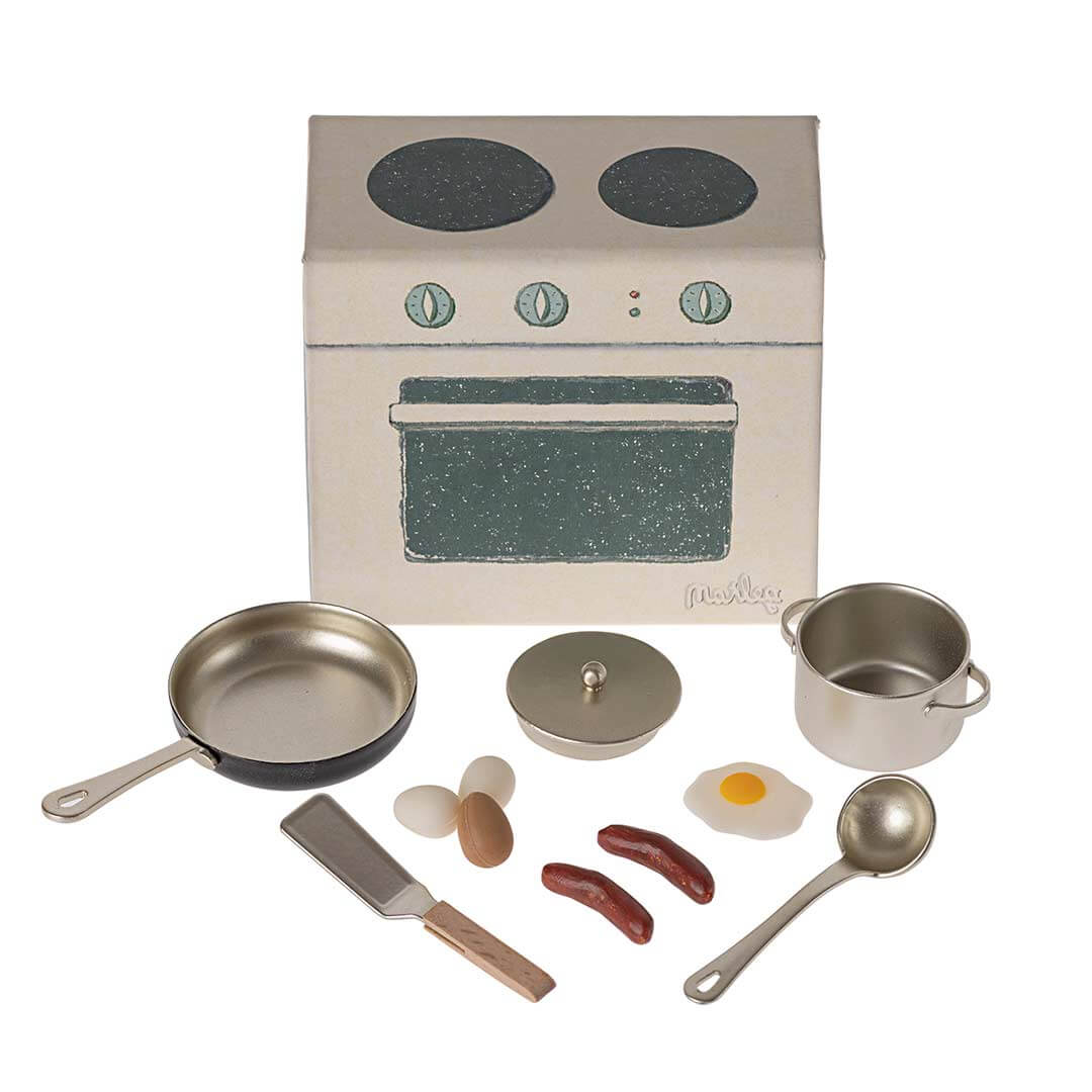 Maileg Dollhouse Stove and Cooking Set with pan, pot with lid, 2 white eggs, one brown egg, 2 sausages, 1 fried egg, spatula, and soup spoon, plus stovetop with 2 burners and 3 knobs