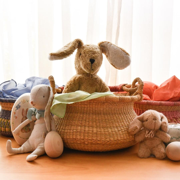 Stuffed Easter bunny toys sit in and around the natural swing bolga basket.
