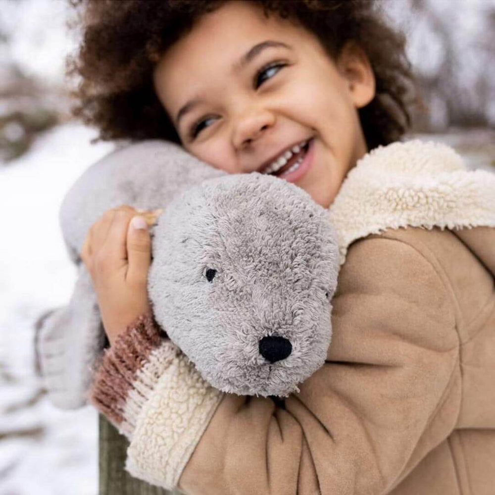 Child holding Organic Grey Seal Warming Pillow