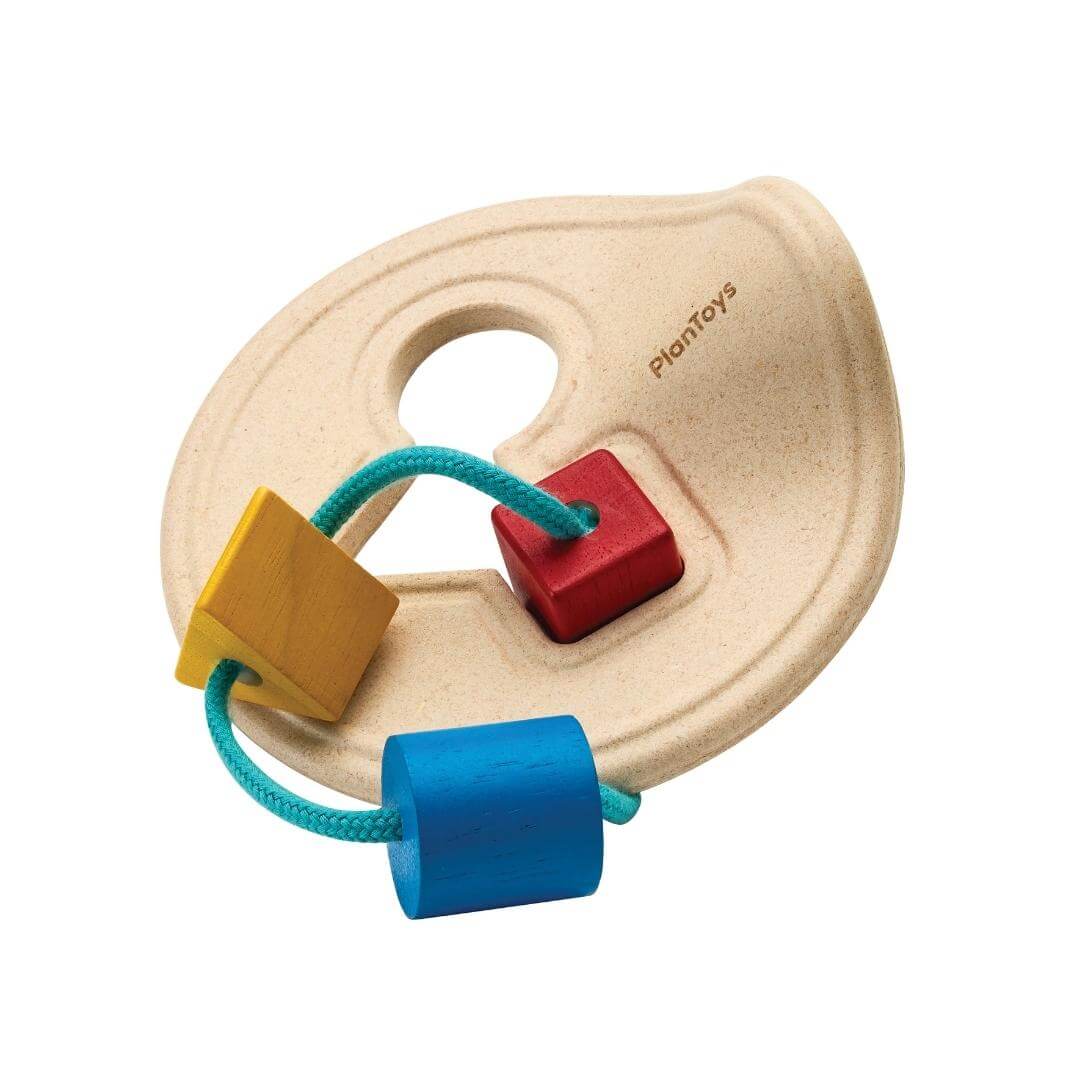 PlanToys Montessori First Shape Sorter with a natural wood base and three colorful shapes; red square, yellow triangle, and blue cylinder, threaded on a teal cord.