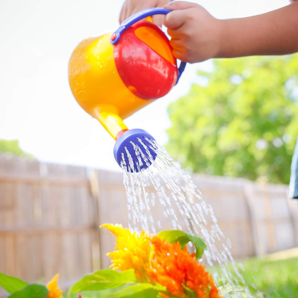 Child pouring water from Spielstabil Watering Can onto orange flowers