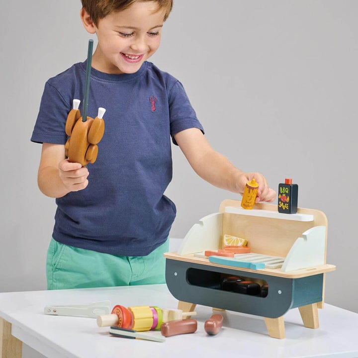 Boy putting play chicken on grill from Tender Leaf Toys Wooden Barbeque Play Set