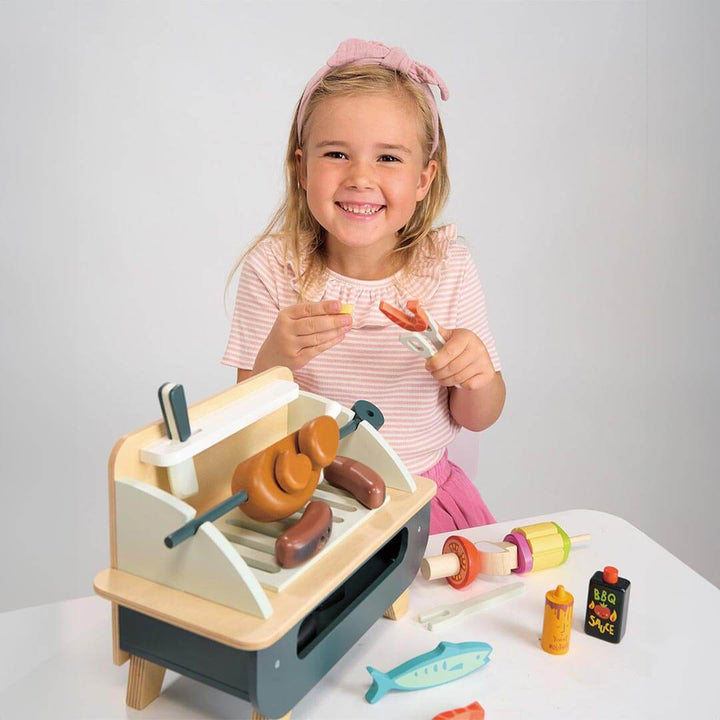 Girl holding shrimp and lemon from Tender Leaf Toys Wooden Barbeque Play Set