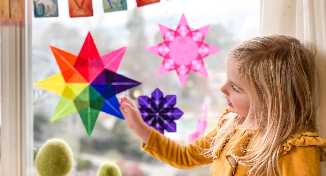 A young girl is holding a kite paper star.