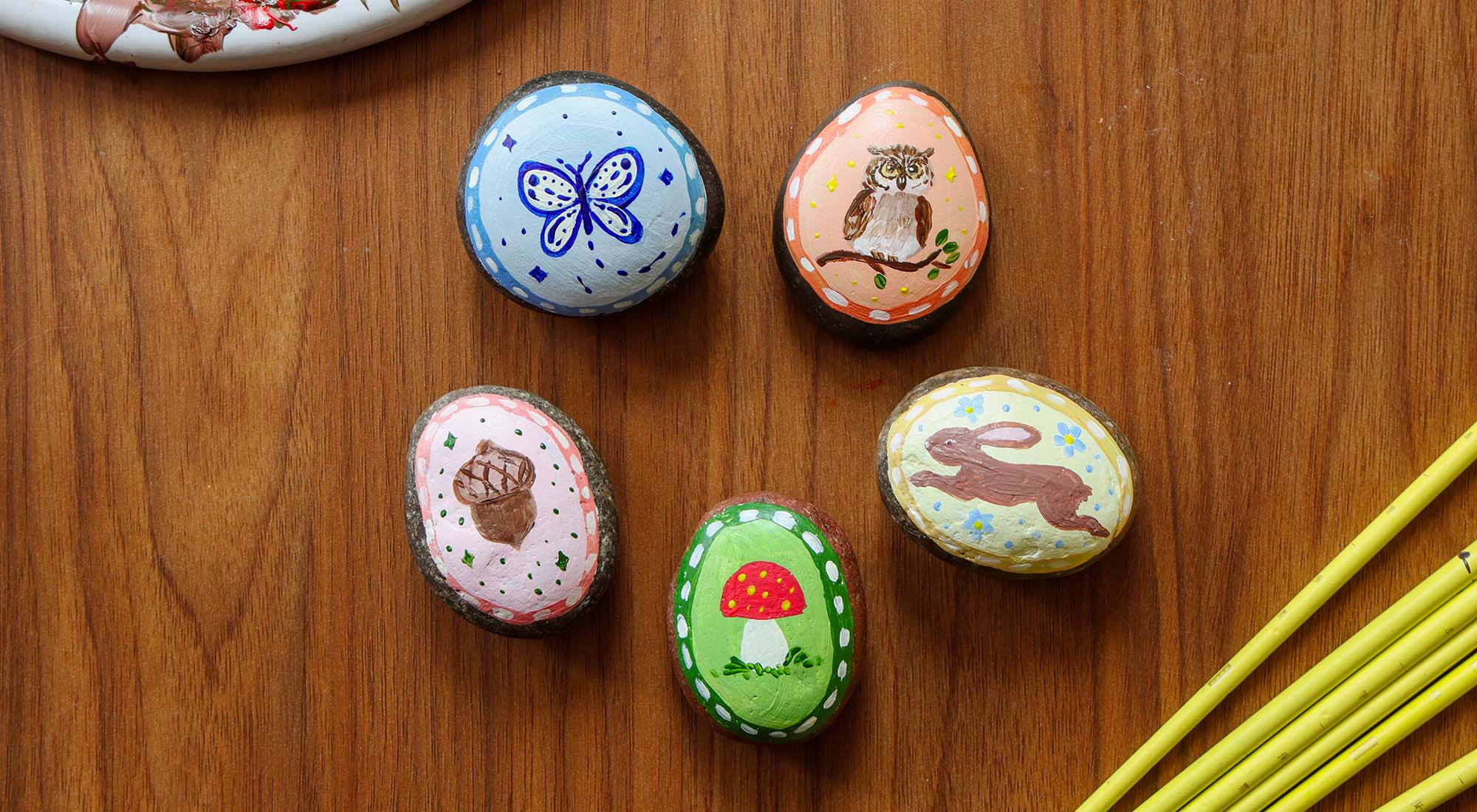 Hand painted story stones on a wooden table.
