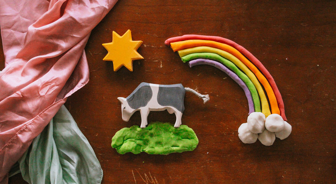 rainbow play dough next to wooden figures and play silks