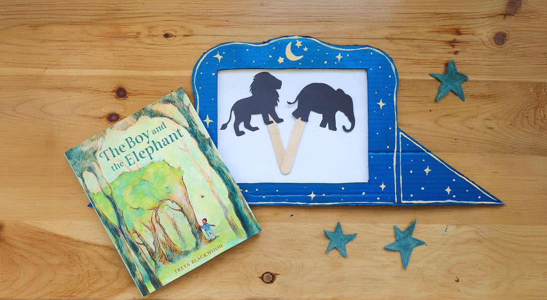 A shadow puppet theater craft on a wooden table with a children's book.