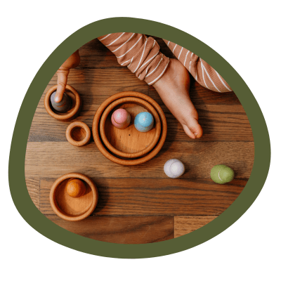 A triangle shape with a kid playing with wooden nesting bowls.