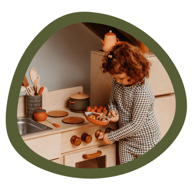 A girl using a wooden kitchen set.
