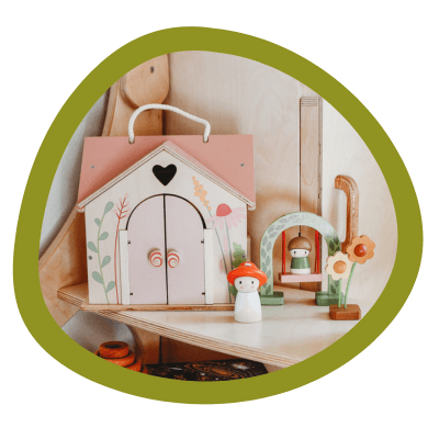 A pink dollhouse with a mushroom figure on a play shelf.