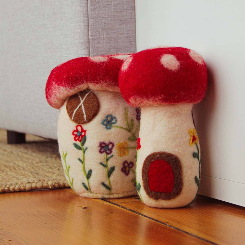 Set Of Two Felted Mushrooms on a hardwood floor next to a grey couch.