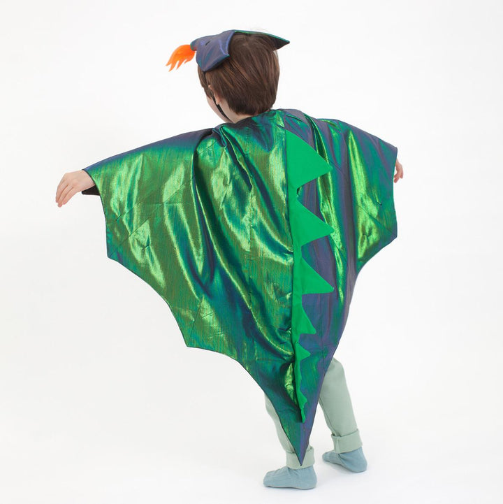 Child wearing the green metallic dragon costume set from Meri Meri with winged cape and dragon headpiece featuring flame detail and embroidered eyes as shown from the back against a white background.