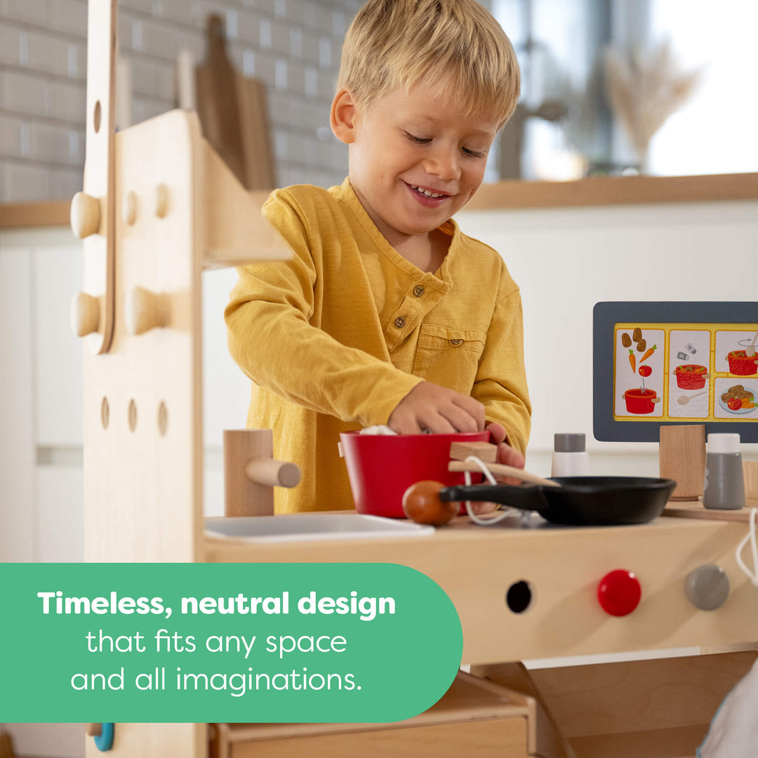 Child playing with a wooden toy kitchen set in a neutral-colored room.