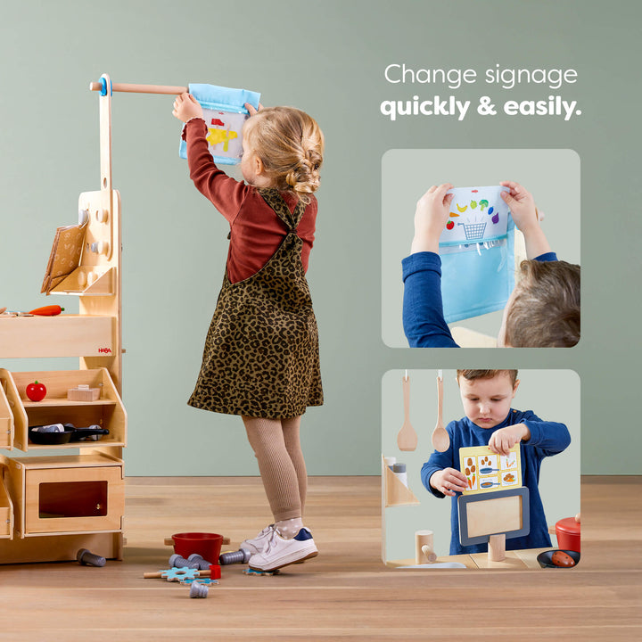 Child changing the sign on the Creative Play 3 in 1 – Play Kitchen, Store & Workshop, with text 'Change signage quickly & easily.'