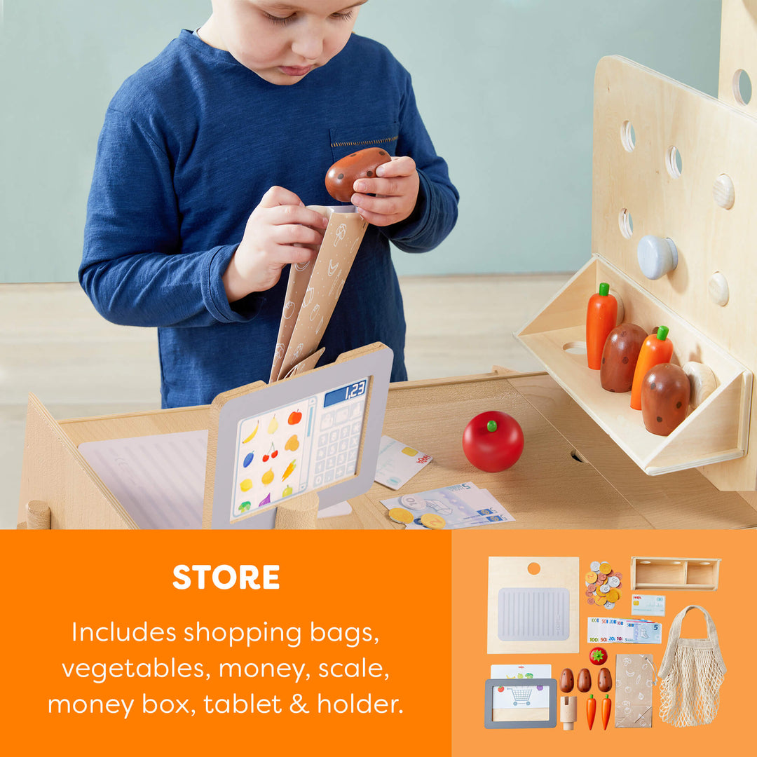 Child playing with a wooden toy set including vegetables, money, and a tablet holder.