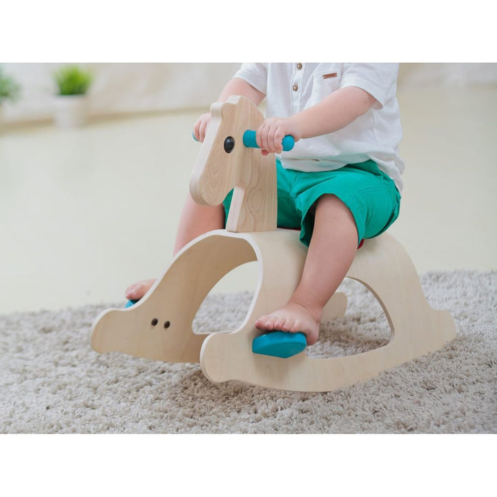 Childs feet on foot rests of PlanToys - Wooden Palomino Rocking Horse - Bella Luna Toys