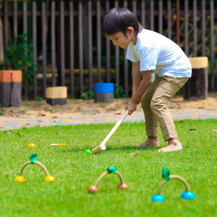 Child hitting ball with mallet from PlanToys USA - Wooden Croquet Set 