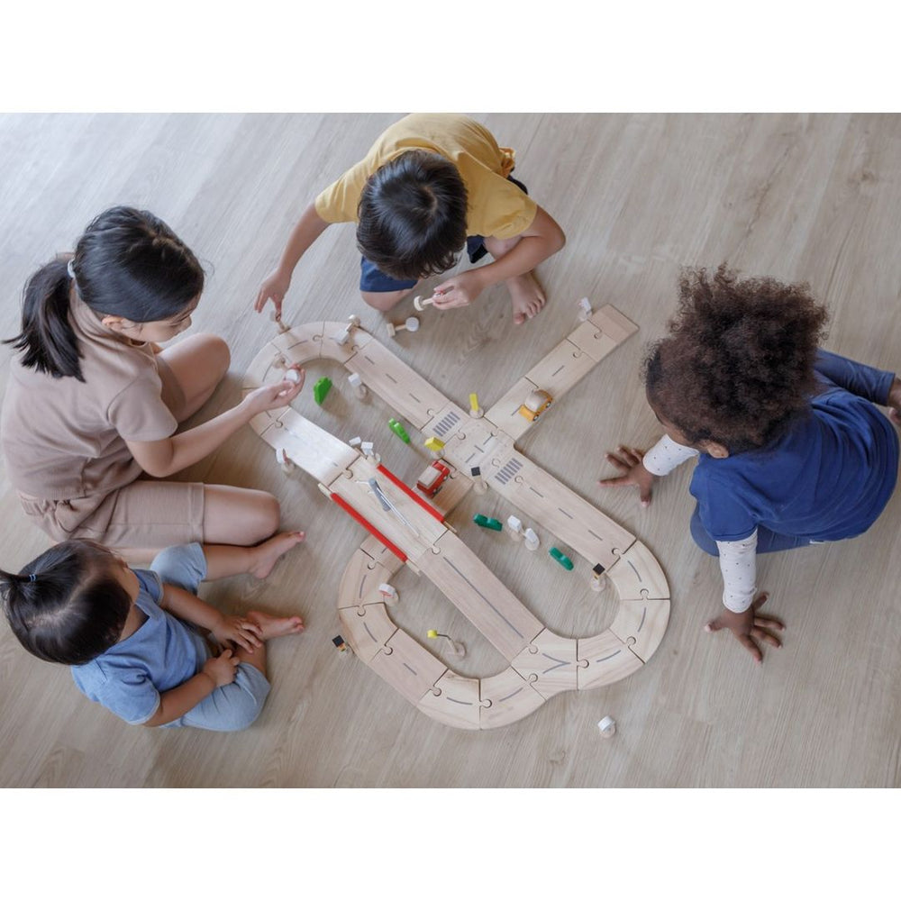 Overhead view of family playing with PlanToys - Wooden Road System Play Set