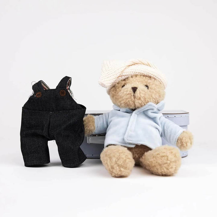 Teddy bear in a blue outfit with a black dog toy on a white background