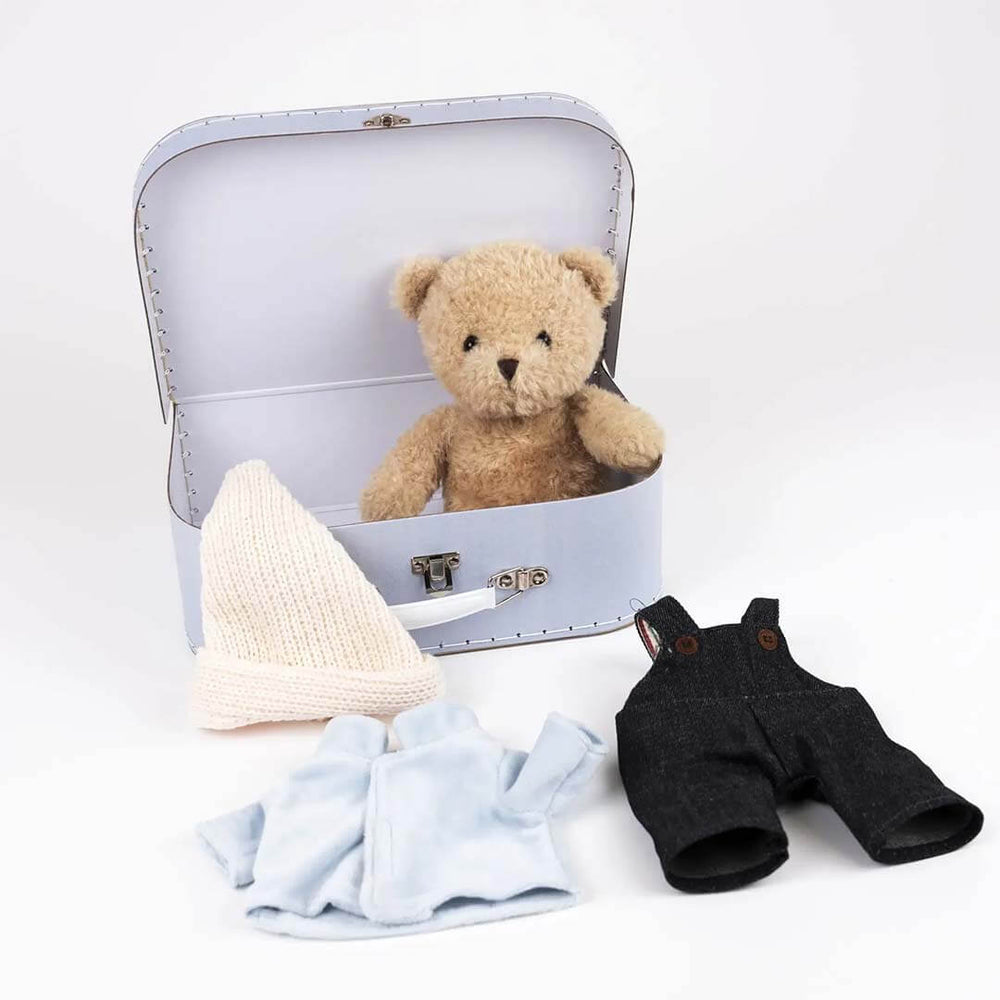 Small suitcase with a teddy bear, baby blanket, and overalls on a white background