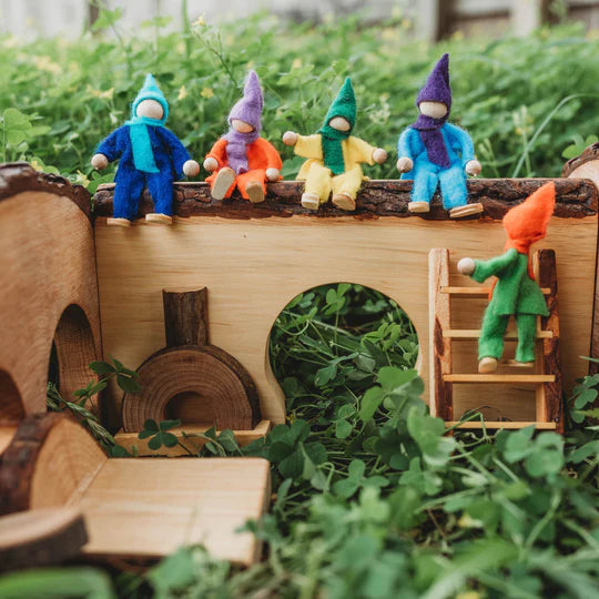 Fairy and gnome toys placed on a wooden dollhouse outside in a forest