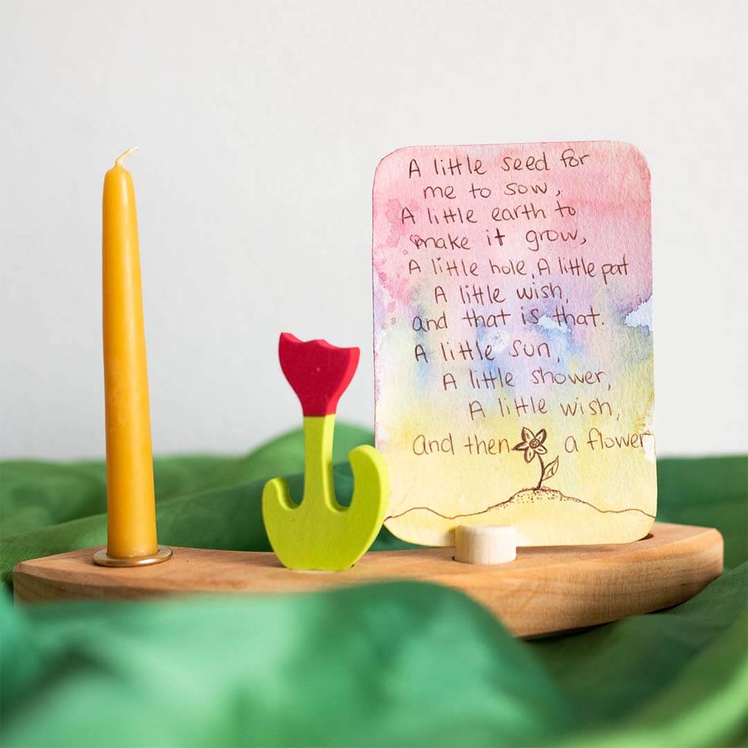 Decorative setup with a candle, wooden stand, and card with text on a green fabric background