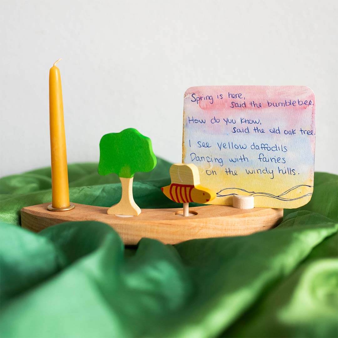 Wooden stand with a candle, tree, fish, and decorative card on a green fabric background