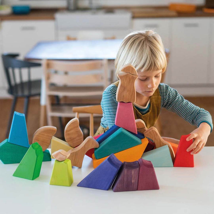 Child playing with colorful wooden blocks on a table in a kitchen setting.