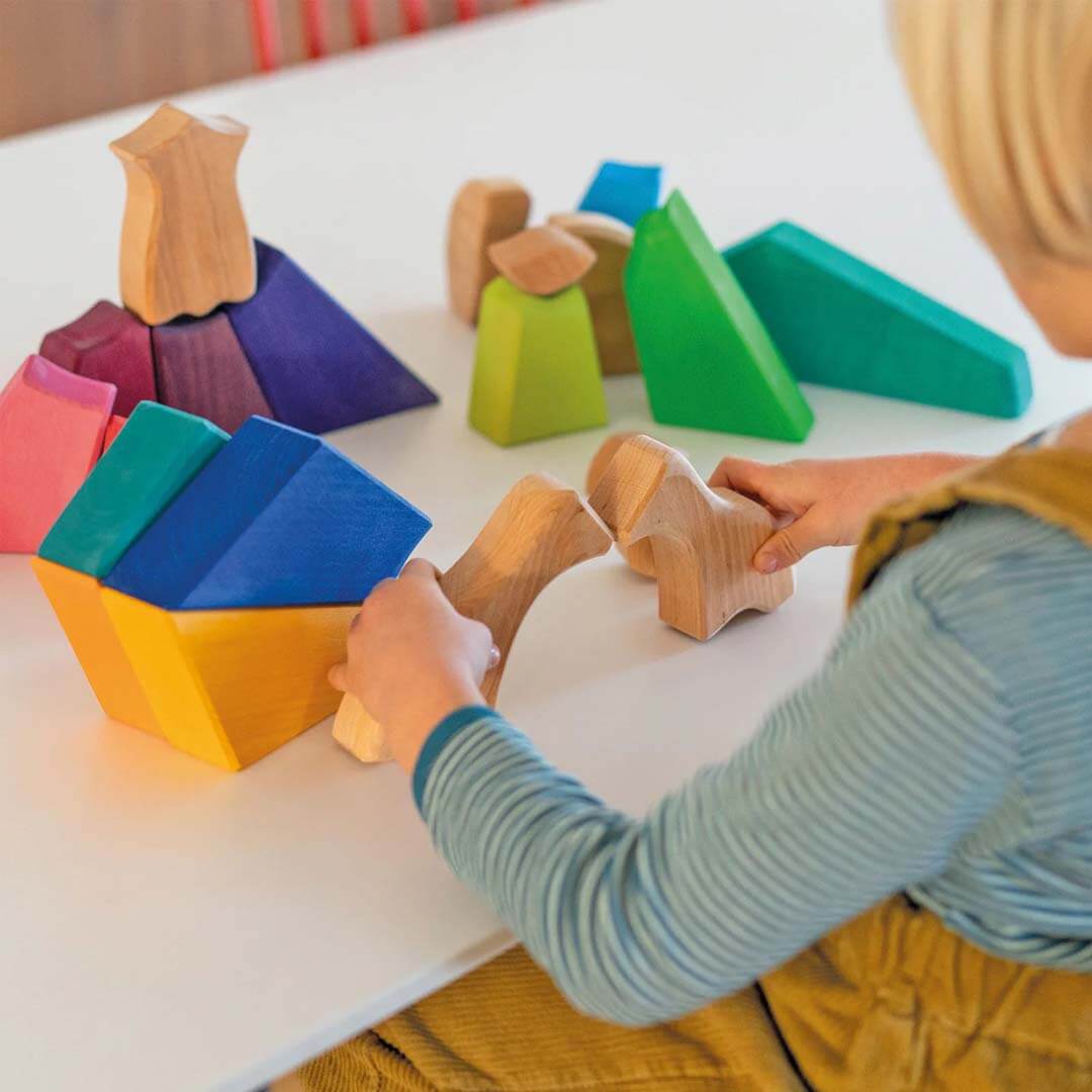 Child playing with colorful wooden blocks on a table.