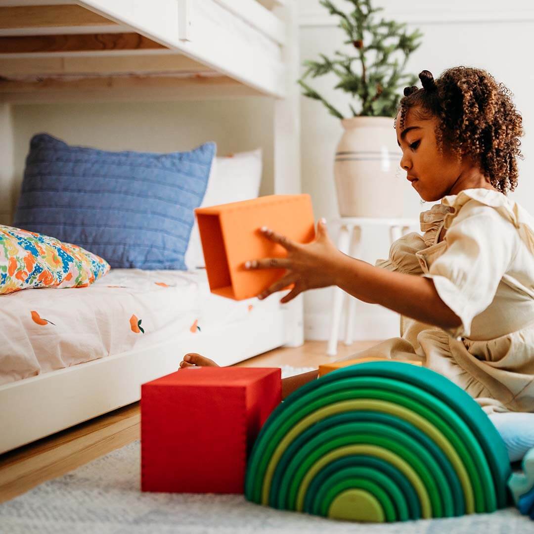 Child playing with colorful blocks in a bedroom.