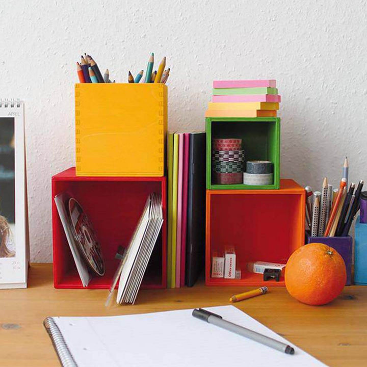 Colorful desk organizer with stationery items on a wooden surface.