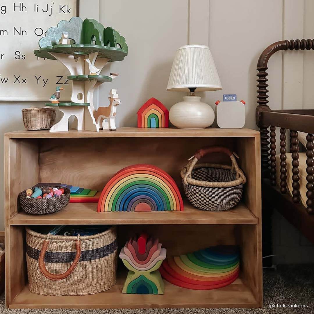 Wooden shelf with children's toys and decor in a room setting.
