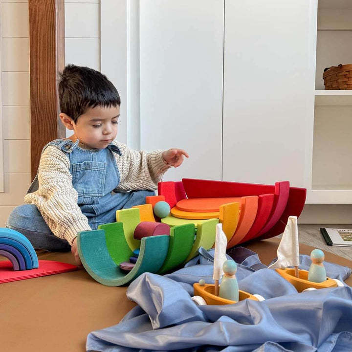 Child playing with colorful toys on a wooden floor.