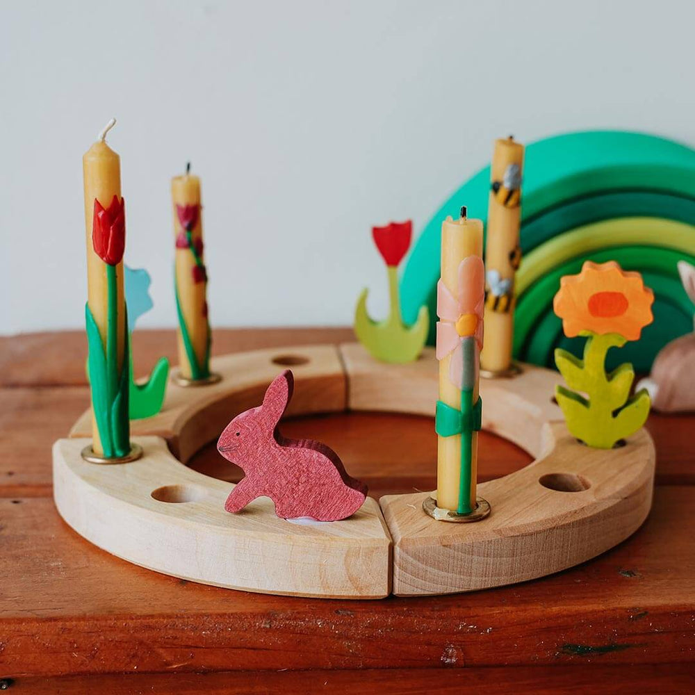 Wooden ring with candles and a rabbit figure on a wooden surface