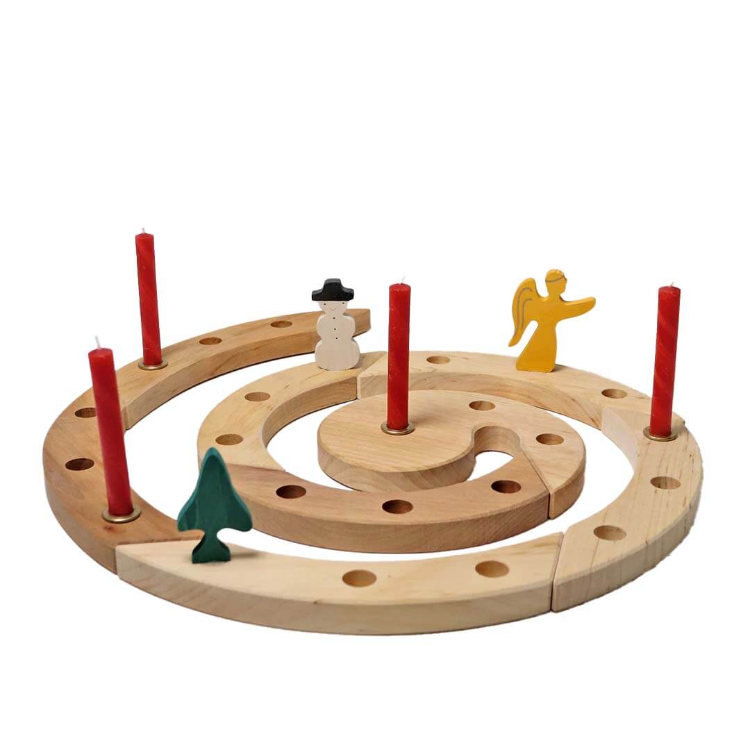 Wooden Advent spiral with red candles and small figurines on a white background.