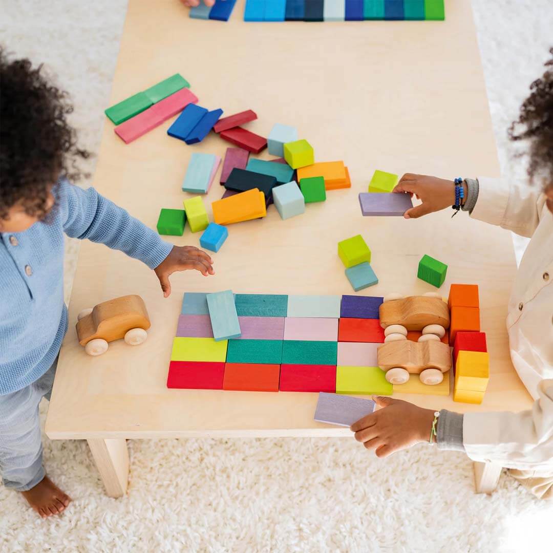 Two children playing with colorful blocks on a table.