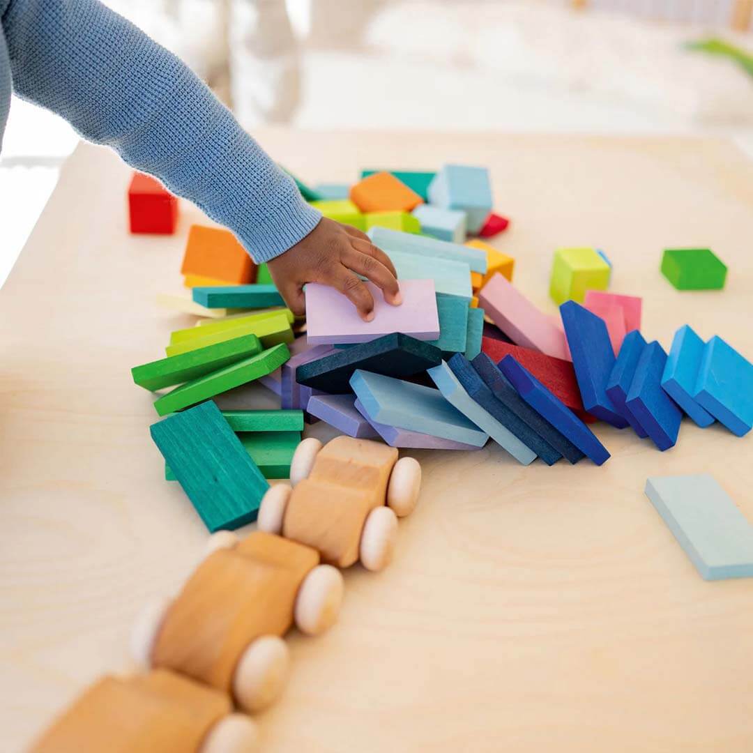 Colorful wooden blocks and a wooden train set on a light surface.