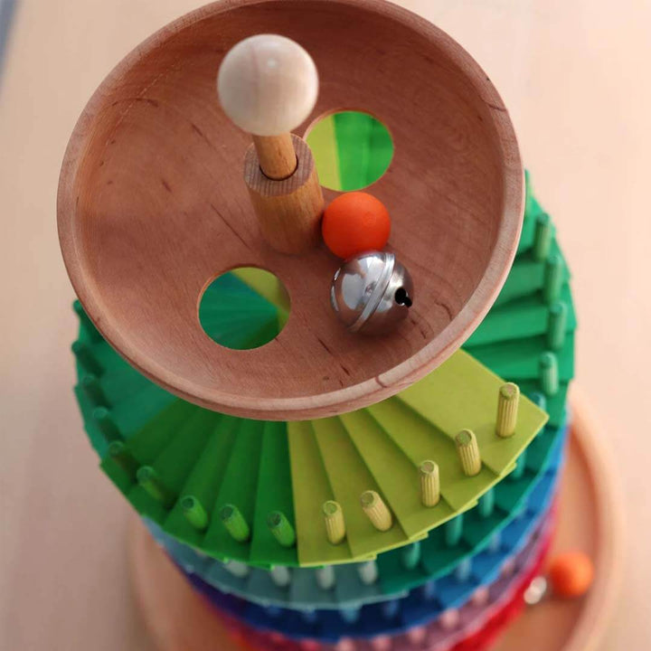 Colorful wooden toy with spinning top and beads on a beige background.