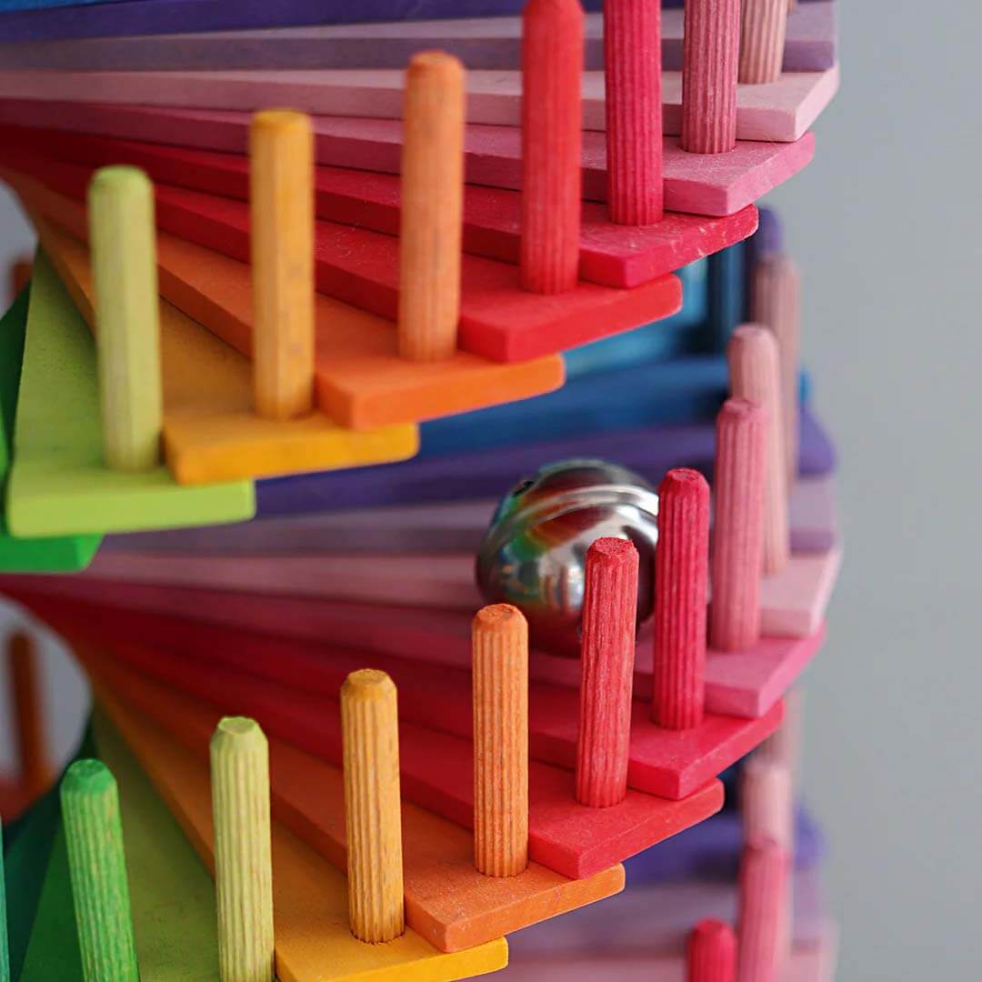 Colorful wooden blocks with a ball inside on a gray background.