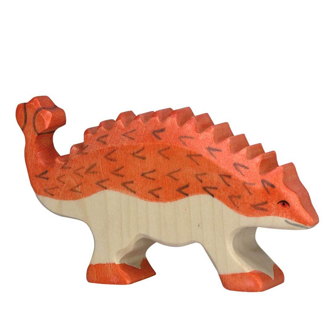 A handcrafted wooden toy dinosaur with a bright orange-red top and feet, and a natural light wood underside, featuring carved black triangular patterns on its back.