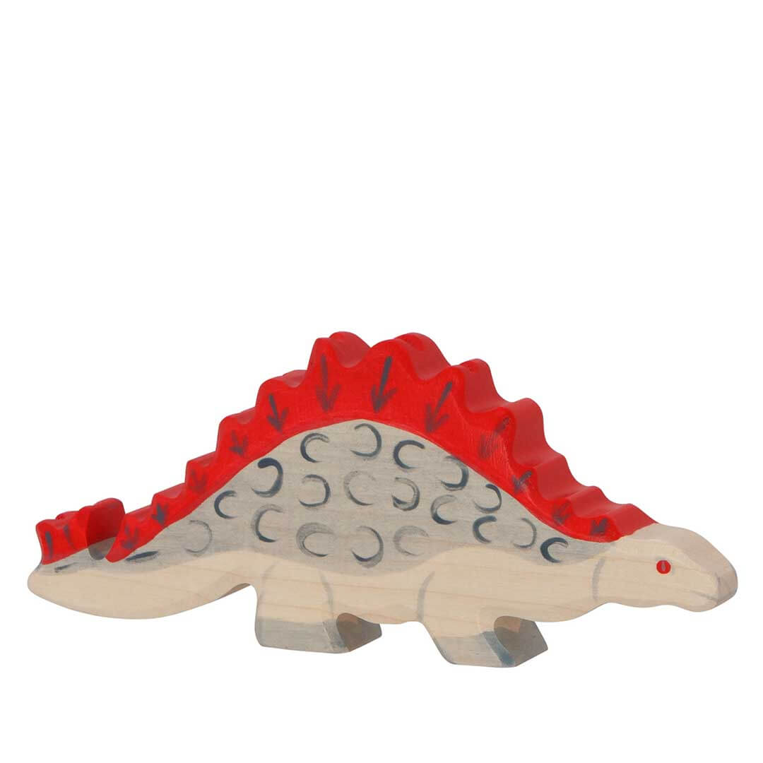 A wooden toy Stegosaurus dinosaur with a natural light wood body, a bright red back and spikes, and dark gray engraved details, shown on a plain white background.